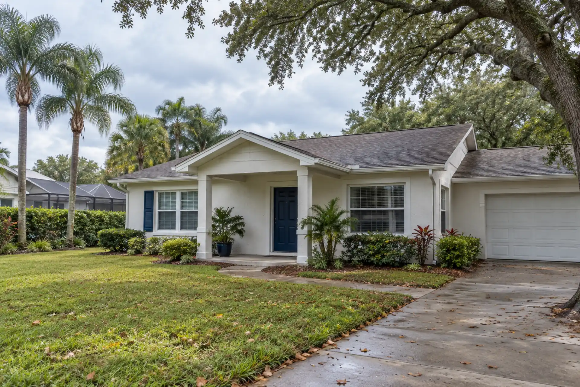 A low stucco bungalow with a shaded porch and navy door.
