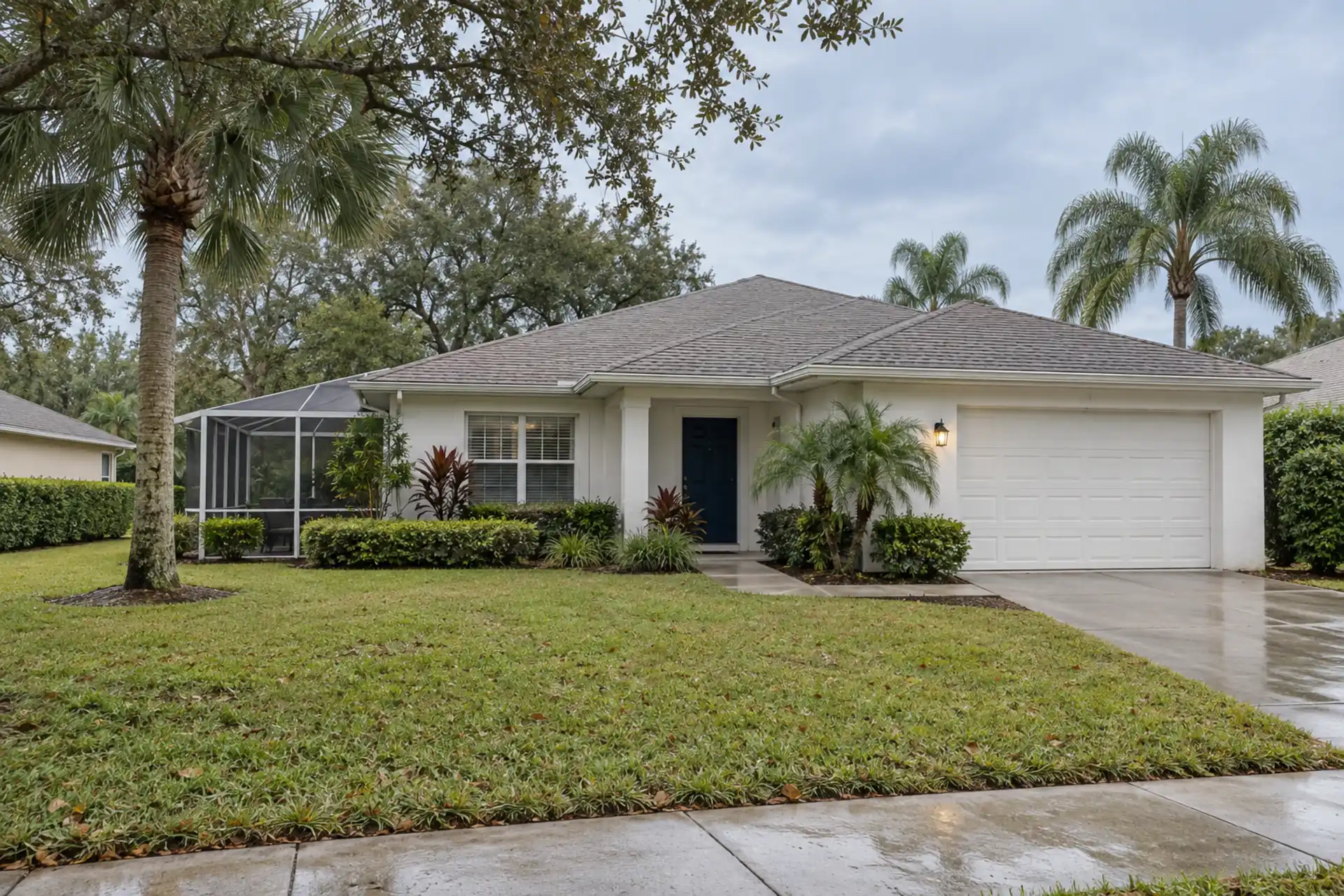 A white stucco ranch with a screened lanai and cabbage palms.